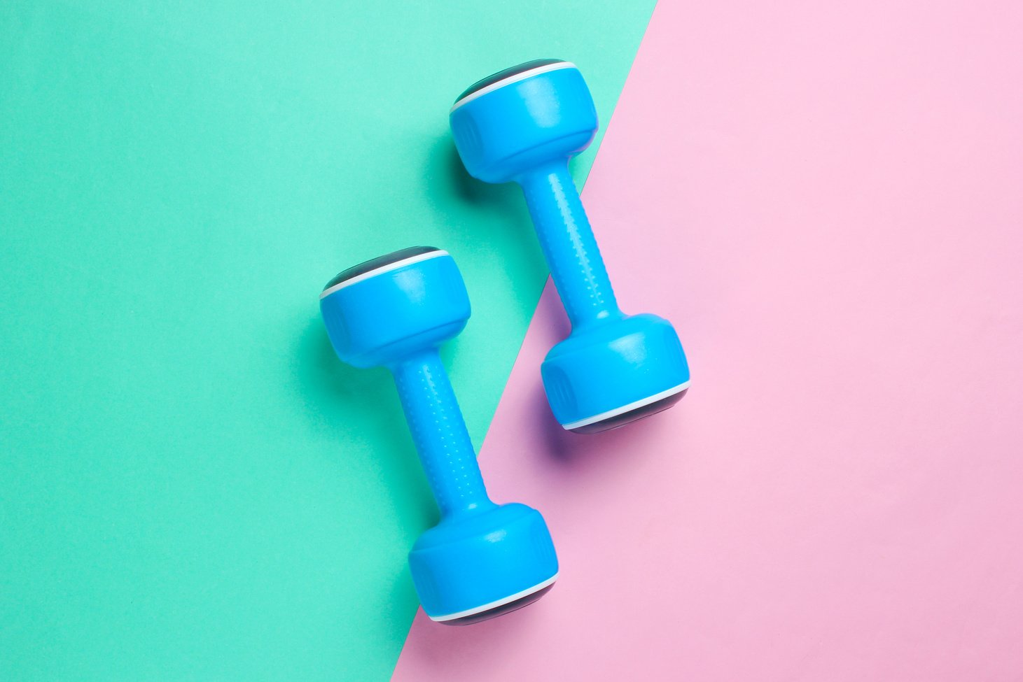 Two blue plastic dumbbells on pastel background Sport, fitness concept. Top view. Flat lay. Minimalism